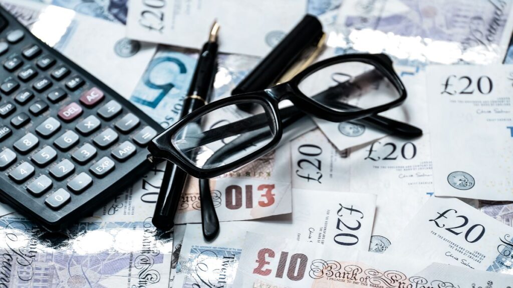 Calculator, glasses, and British pound notes representing financial analysis and the hidden costs of UK pension transfers.