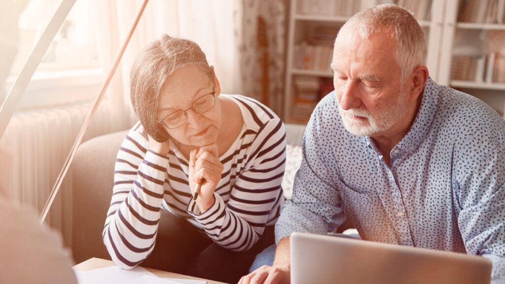 Mature couple reviewing pension documents with an advisor, representing US executives managing dormant UK pensions.