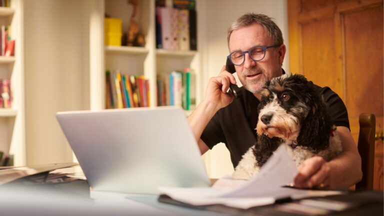 Man reviewing finances and speaking on the phone at home office