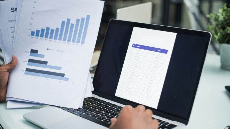 Reviewing multiple financial reports and pension documents on a laptop
