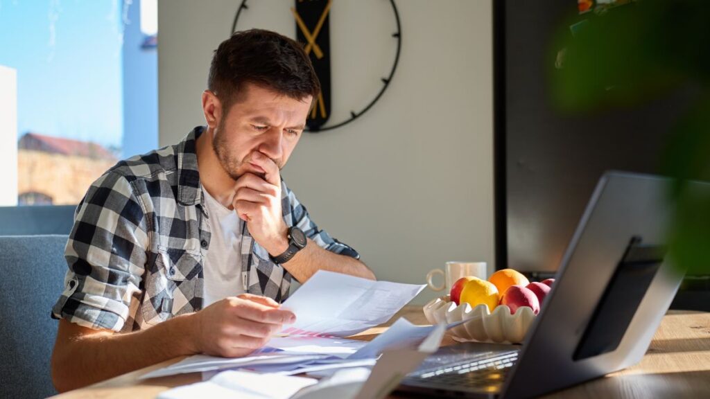 Man reviewing financial documents and planning decisions at home