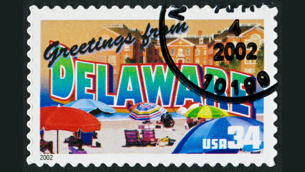 Vintage USA postage stamp featuring “Greetings from Delaware” with beach umbrellas and coastal scene, 2002